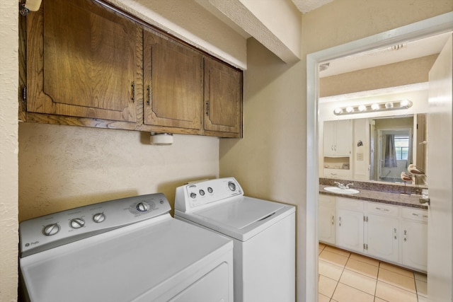 clothes washing area featuring washer and dryer, light tile patterned flooring, cabinets, and sink