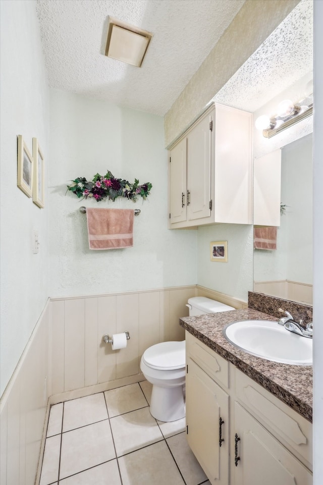 bathroom featuring vanity, tile patterned floors, a textured ceiling, and toilet