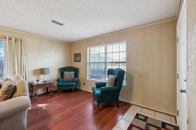 living area with hardwood / wood-style floors, ornamental molding, and a textured ceiling