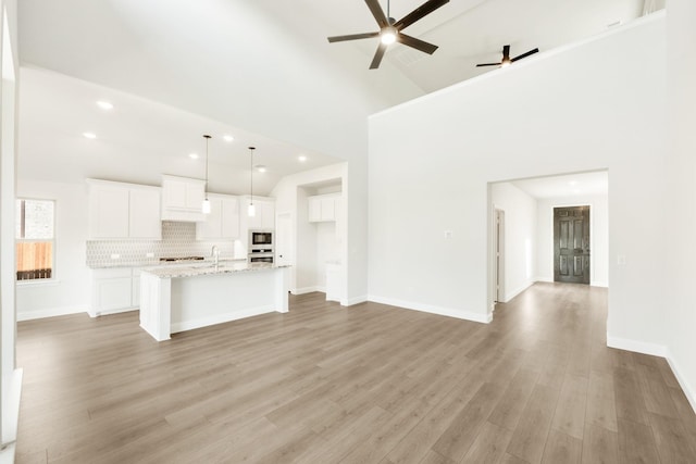 kitchen with stainless steel appliances, light stone countertops, hanging light fixtures, and white cabinetry