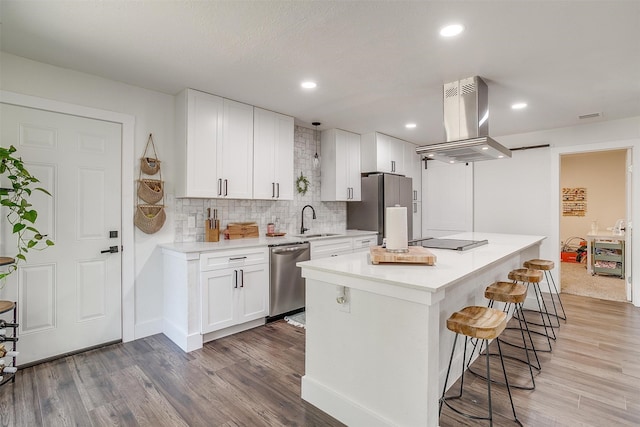 kitchen with sink, wood-type flooring, island exhaust hood, white cabinetry, and appliances with stainless steel finishes