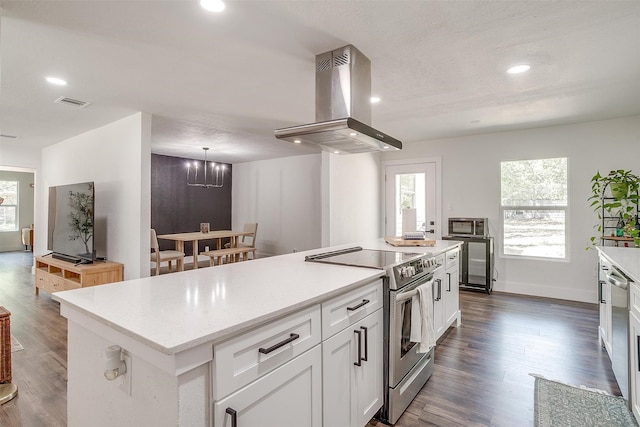 kitchen featuring dark wood-type flooring, ventilation hood, white cabinetry, hanging light fixtures, and stainless steel appliances