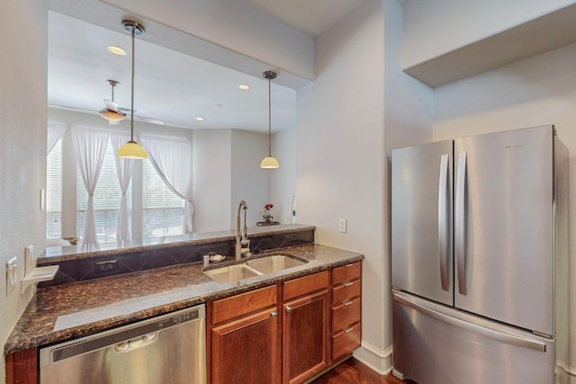 kitchen with dark wood-type flooring, sink, appliances with stainless steel finishes, decorative light fixtures, and dark stone countertops