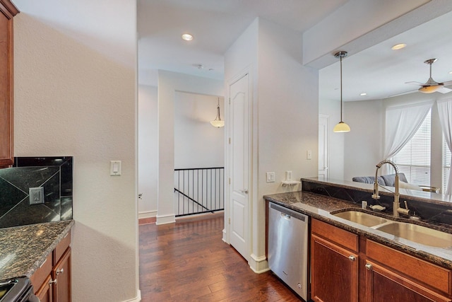 kitchen featuring sink, appliances with stainless steel finishes, dark stone counters, hanging light fixtures, and dark hardwood / wood-style flooring