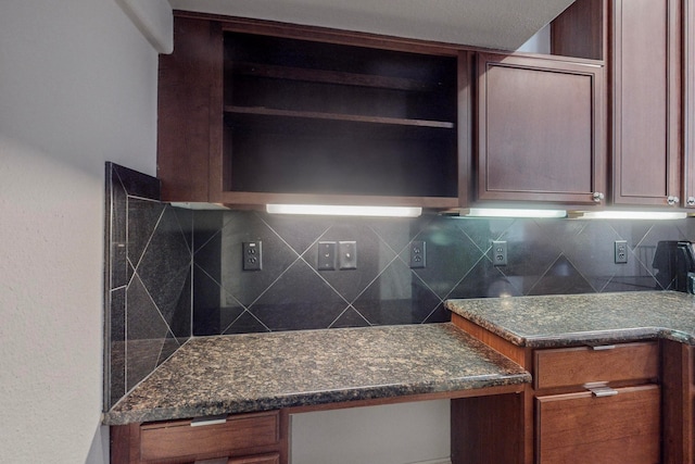 kitchen featuring dark stone counters, backsplash, and built in desk