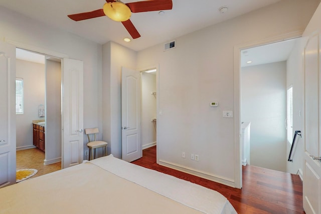 bedroom featuring ensuite bathroom, multiple windows, hardwood / wood-style flooring, and ceiling fan