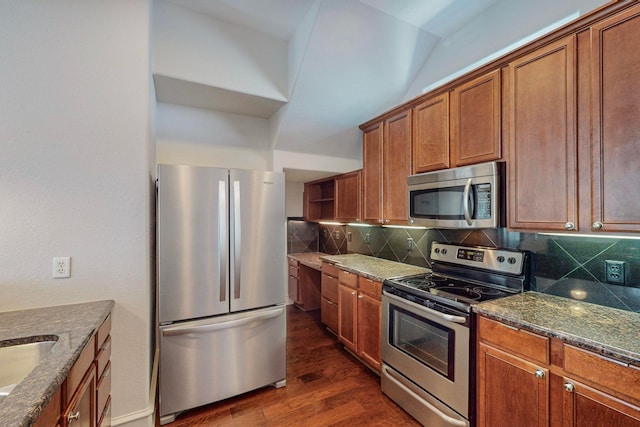 kitchen featuring stainless steel appliances, dark stone counters, backsplash, and dark hardwood / wood-style flooring