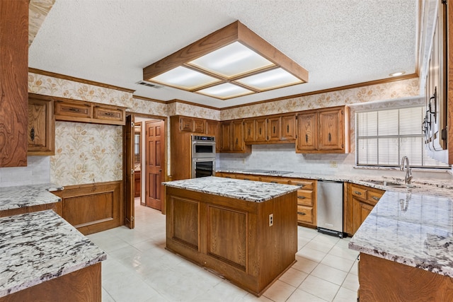 kitchen with a center island, sink, a textured ceiling, appliances with stainless steel finishes, and light stone counters