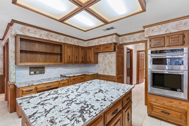 kitchen featuring a kitchen island, light stone countertops, a textured ceiling, double oven, and light tile patterned flooring