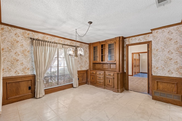 unfurnished dining area featuring a textured ceiling, crown molding, and a notable chandelier