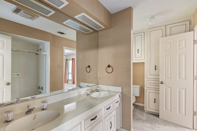 full bathroom featuring vanity, bath / shower combo with glass door, a textured ceiling, and toilet