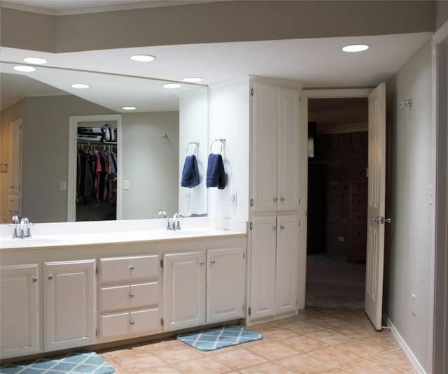 full bathroom with double vanity, a spacious closet, a sink, and recessed lighting