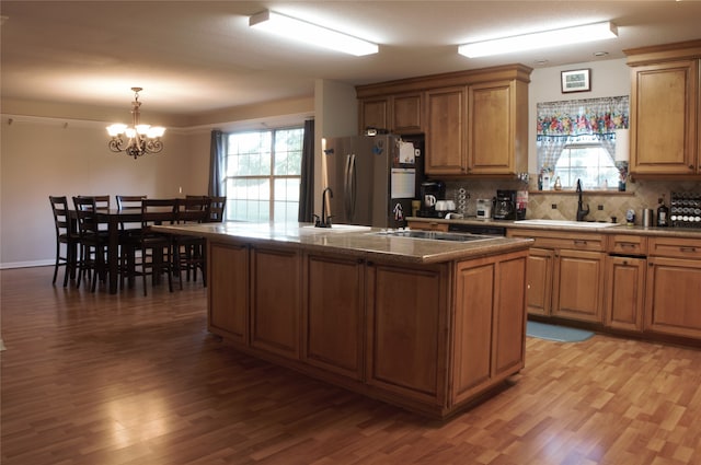 kitchen with tasteful backsplash, freestanding refrigerator, a sink, and light wood finished floors