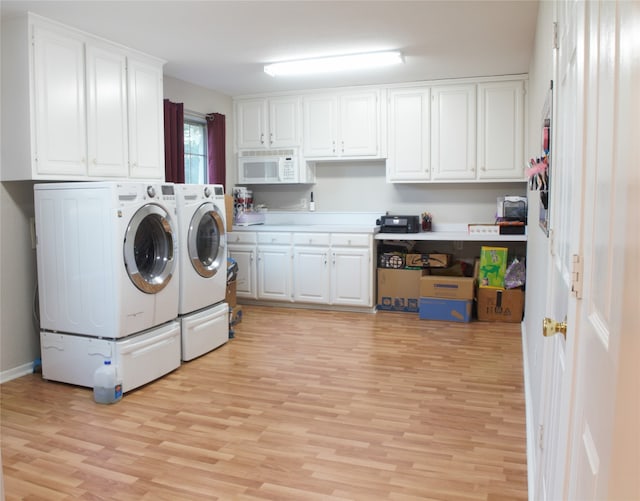 laundry area with light wood-type flooring, cabinet space, and washing machine and clothes dryer