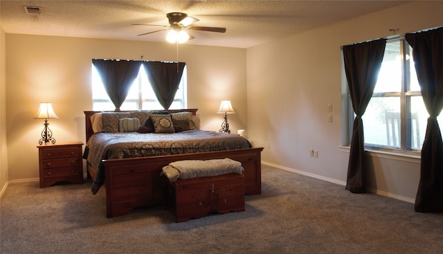 carpeted bedroom featuring a textured ceiling, multiple windows, and visible vents