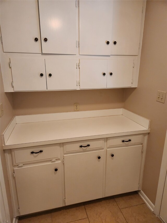 interior space featuring light tile patterned floors and white cabinetry