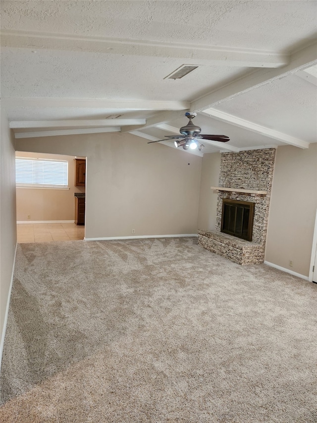 unfurnished living room featuring ceiling fan, light carpet, a large fireplace, vaulted ceiling with beams, and a textured ceiling