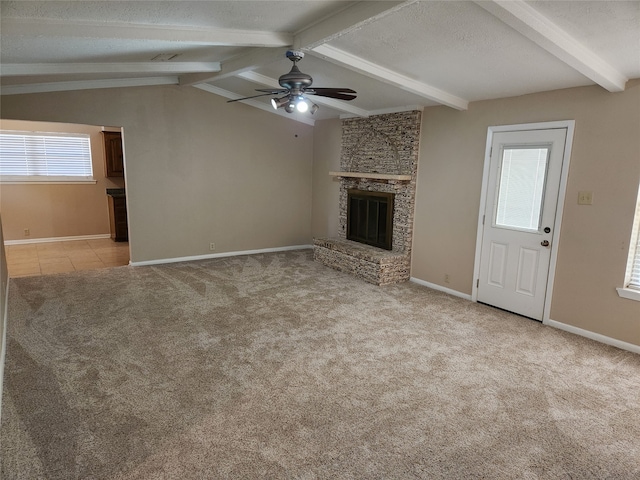 unfurnished living room with ceiling fan, a brick fireplace, a textured ceiling, lofted ceiling with beams, and light carpet