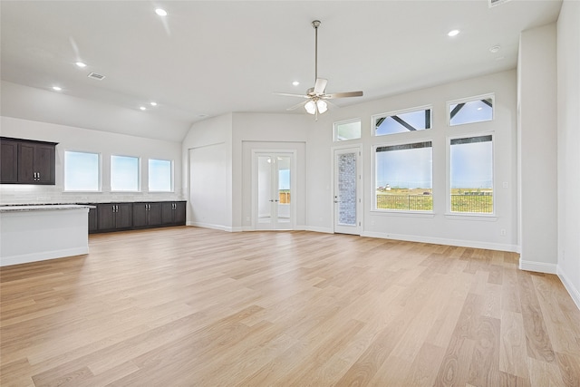 unfurnished living room featuring ceiling fan, a healthy amount of sunlight, light hardwood / wood-style floors, and vaulted ceiling