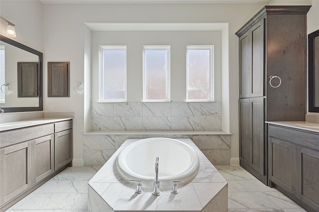 bathroom featuring a relaxing tiled tub, a healthy amount of sunlight, and vanity