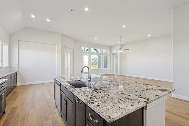 kitchen with ceiling fan, sink, light stone countertops, light hardwood / wood-style flooring, and a kitchen island with sink