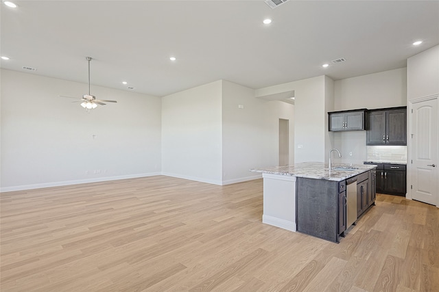 kitchen featuring sink, light hardwood / wood-style flooring, ceiling fan, and an island with sink