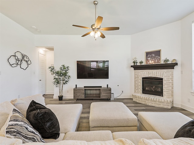 living room featuring ceiling fan, dark hardwood / wood-style floors, and a fireplace