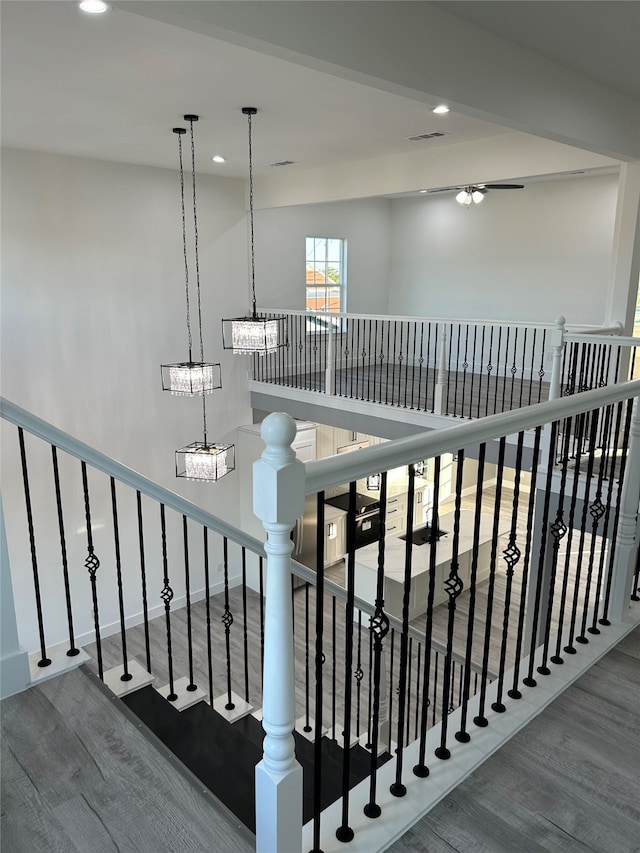 stairway with a notable chandelier and wood-type flooring