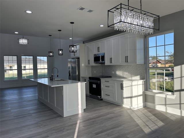 kitchen with white cabinetry, stainless steel appliances, wood-type flooring, and an island with sink