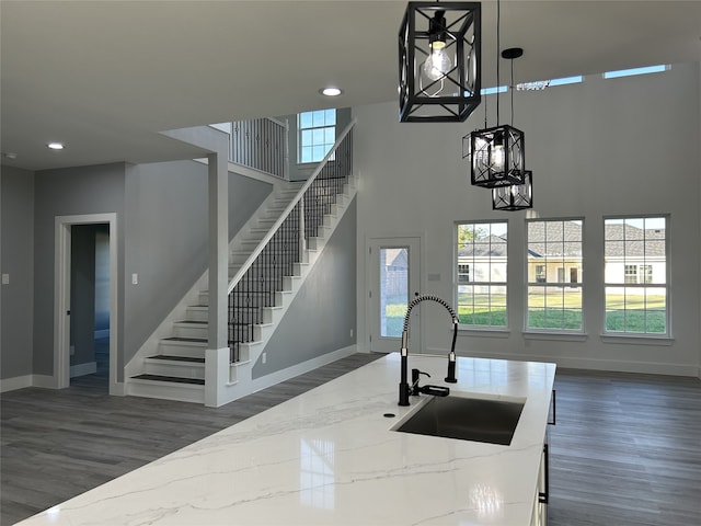 kitchen featuring an island with sink, hanging light fixtures, stainless steel appliances, light stone countertops, and white cabinetry