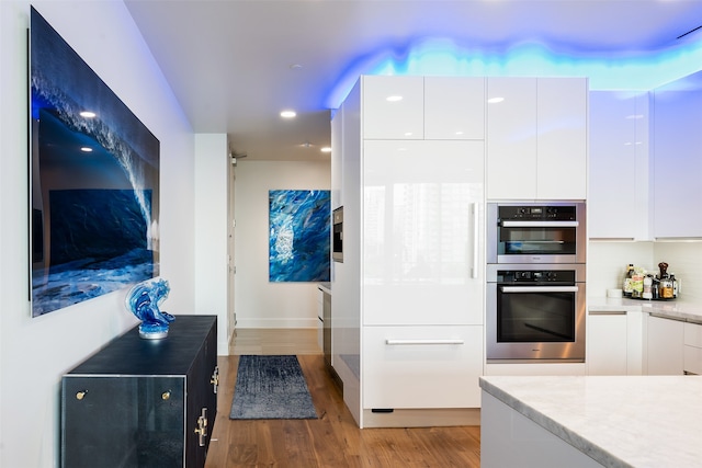 kitchen with double oven, light hardwood / wood-style floors, and white cabinetry