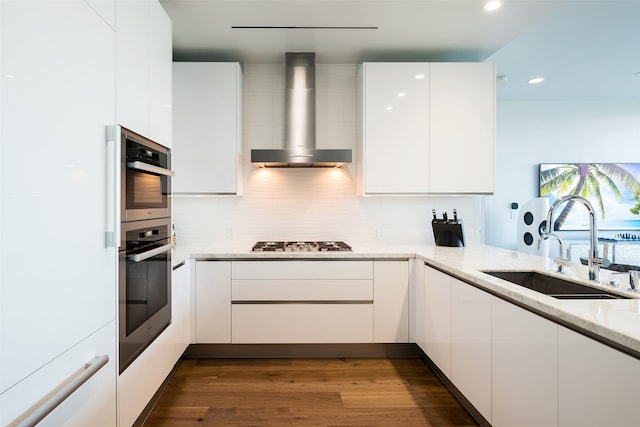 kitchen featuring light stone counters, white cabinets, sink, dark wood-type flooring, and wall chimney range hood