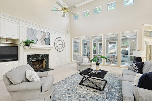 living room featuring ceiling fan, a fireplace, a towering ceiling, and a healthy amount of sunlight