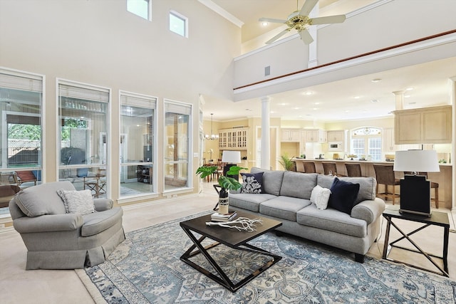 living room with ceiling fan with notable chandelier, a towering ceiling, and a wealth of natural light