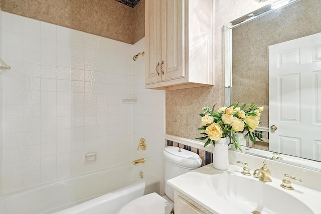 full bathroom featuring vanity, tiled shower / bath combo, and toilet