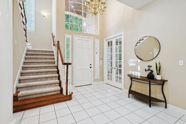 entrance foyer with french doors, an inviting chandelier, a towering ceiling, and light tile patterned floors