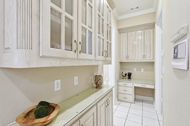 kitchen featuring ornamental molding, built in desk, white cabinetry, and light tile patterned floors