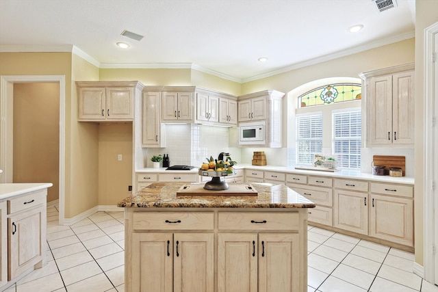 kitchen featuring tasteful backsplash, a kitchen island, white microwave, light tile patterned floors, and ornamental molding