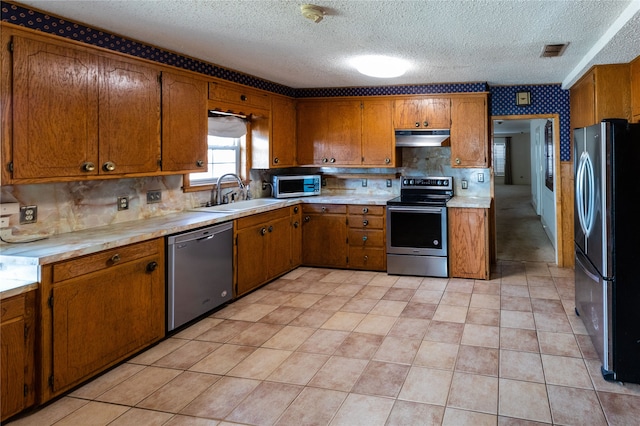 kitchen with a textured ceiling, tasteful backsplash, sink, and stainless steel appliances