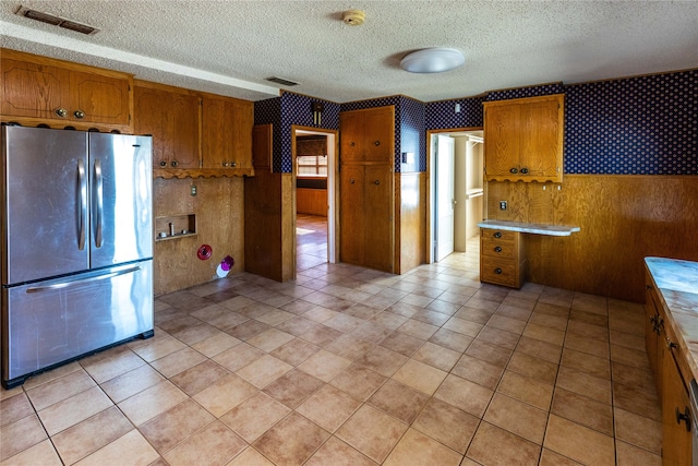 kitchen featuring wood walls, stainless steel fridge, and a textured ceiling