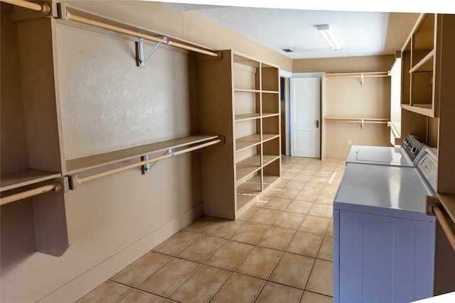 walk in closet with washing machine and clothes dryer and light tile patterned floors