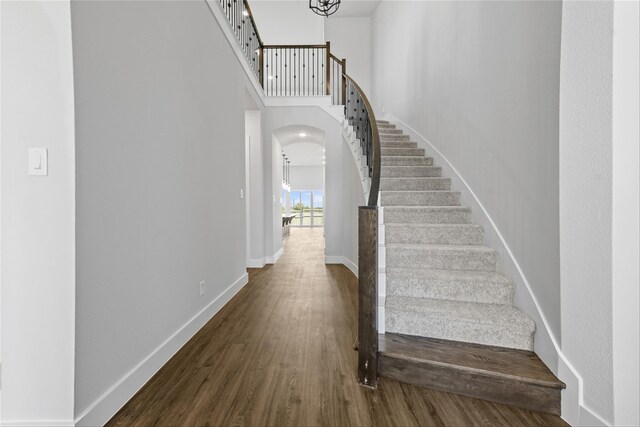 stairs featuring hardwood / wood-style floors and a notable chandelier