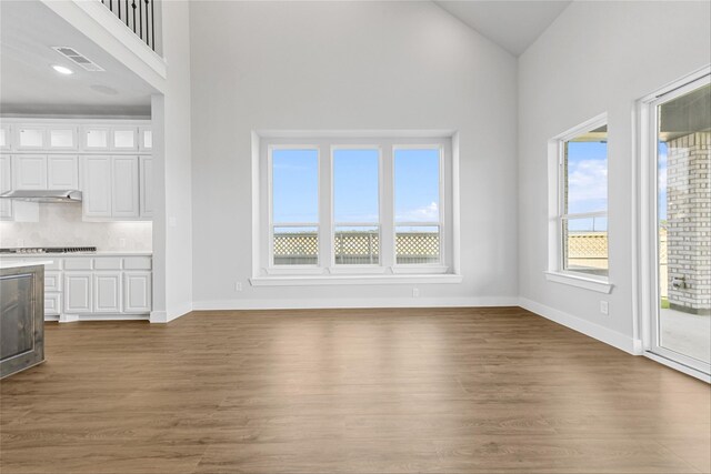 unfurnished living room featuring dark wood-type flooring and high vaulted ceiling