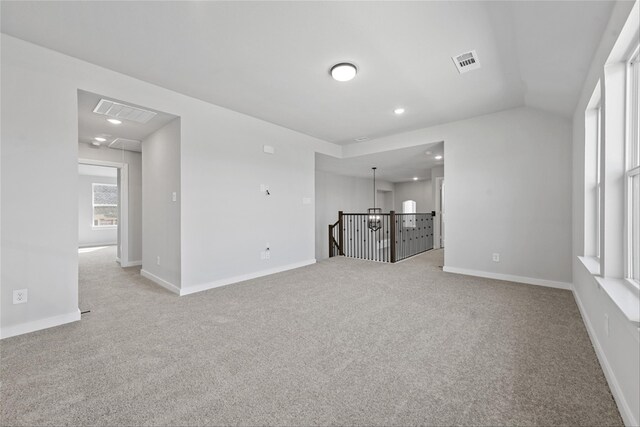 carpeted spare room featuring vaulted ceiling