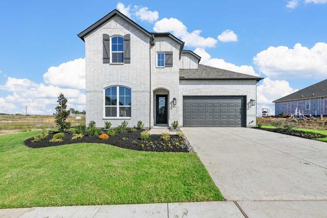 french country style house with a front lawn and a garage