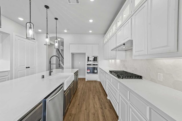 kitchen featuring white cabinets, appliances with stainless steel finishes, dark hardwood / wood-style floors, and hanging light fixtures