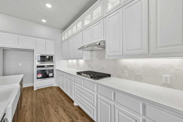 kitchen featuring white cabinets, decorative backsplash, dark hardwood / wood-style flooring, and stainless steel appliances