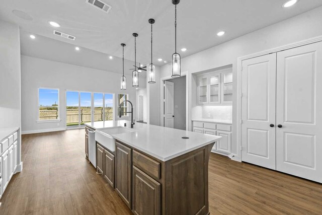 kitchen with white cabinetry, a center island with sink, stainless steel dishwasher, and dark hardwood / wood-style floors