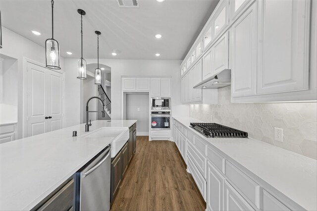 kitchen with white cabinetry, decorative light fixtures, dark hardwood / wood-style floors, and appliances with stainless steel finishes