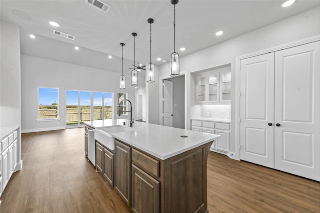 kitchen featuring white cabinets, dishwasher, dark wood-type flooring, and an island with sink